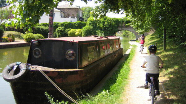 Children cycling along a canal towpath next to a boat