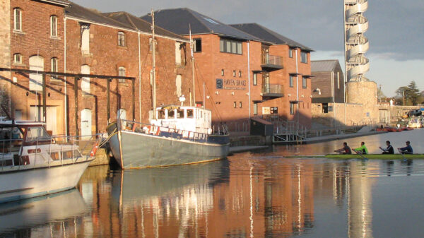 Moored boats and rowers at Exeter basin on the Exeter Ship canal.