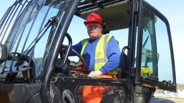 Volunteer in high vis driving a JCB