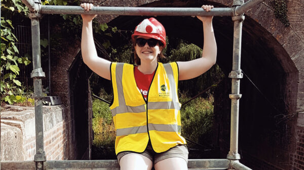 Female in mid-20s sitting on scaffolding - International Women's Day