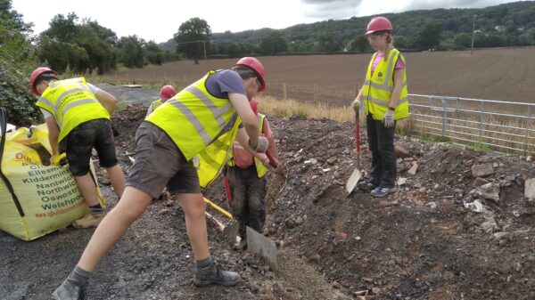 Volunteers in high viz digging in a channel