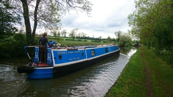 Person steering narrow boat along canal